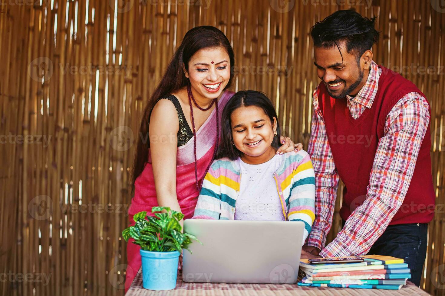 skön traditionell indisk familj lyckligt använder sig av bärbar dator till kolla upp de examen märken av deras glad liten dotter foto