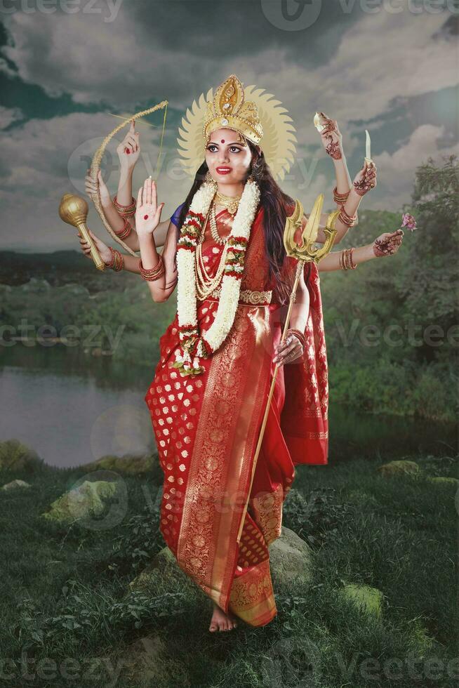 indisk gudinna durga med åtta händer stående nära de sjö i röd saree foto