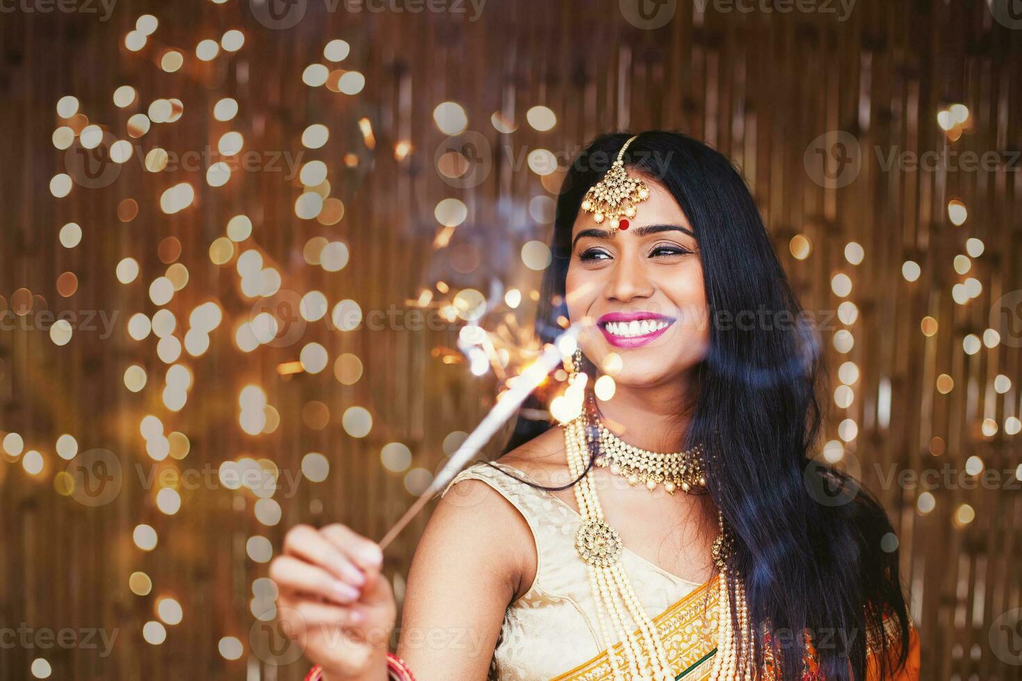 skön indisk kvinna i traditionell kläder innehav en sparkler i de kväll till fira diwali festival foto