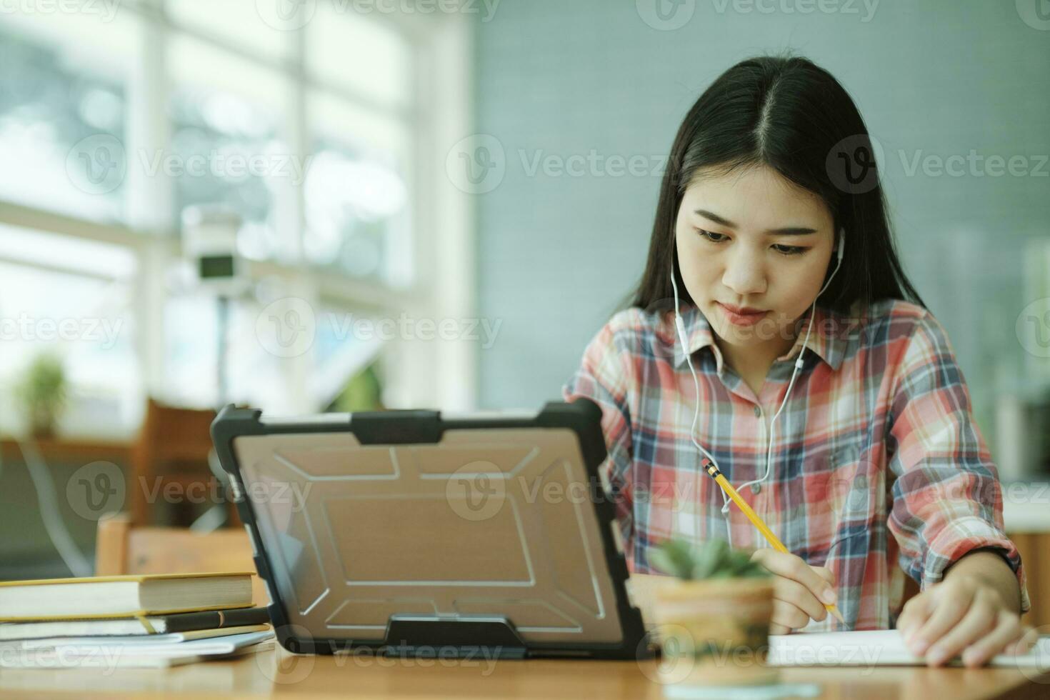 ung asiatisk kvinna studie i främre av de bärbar dator dator och och använder sig av hörlurar på utanför platsen. foto