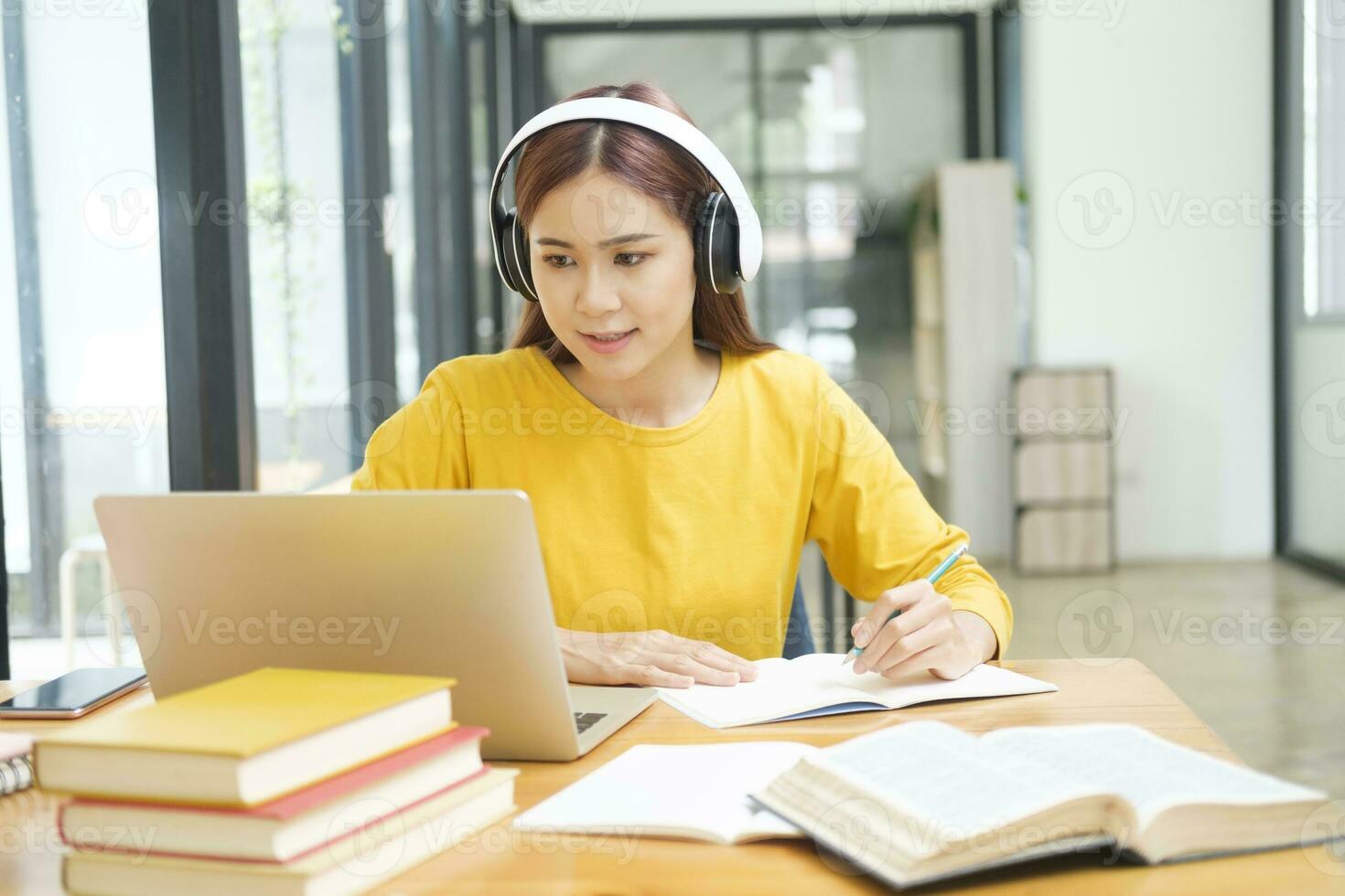 kvinna inlärning uppkopplad använder sig av bärbar dator och skrivning anteckningar. foto