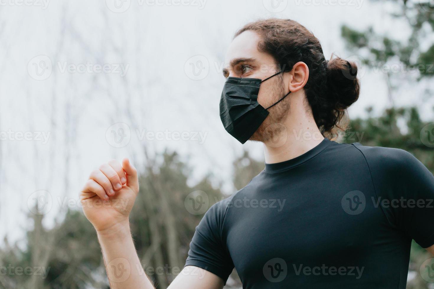 en närbild av en ung man som springer i parken medan du använder en ansiktsmask foto