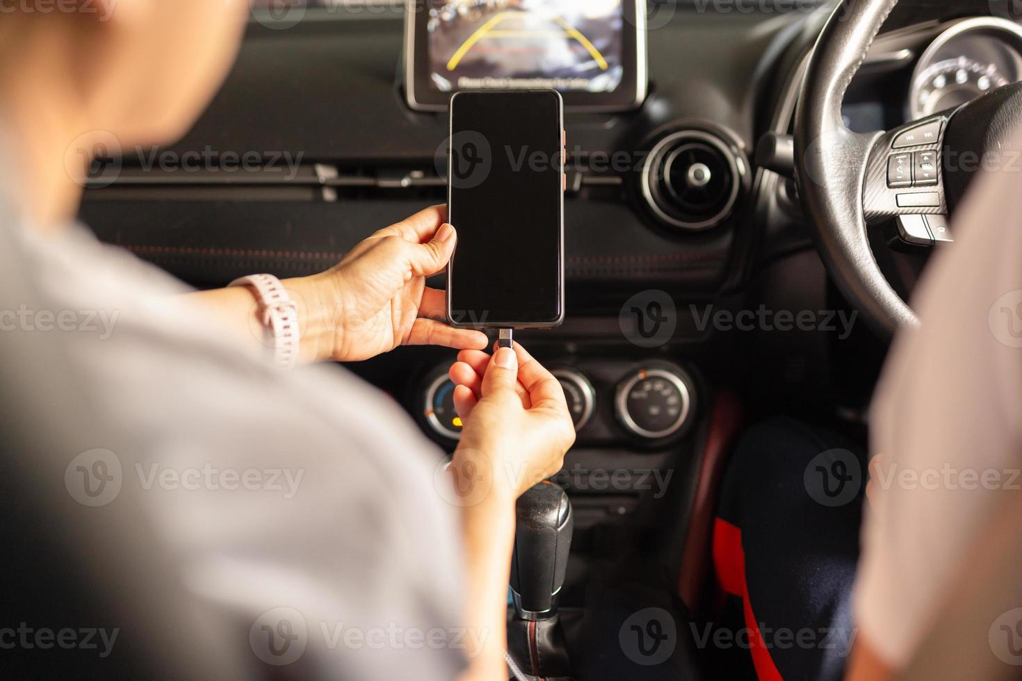 kvinna som laddar batteriets smarta telefon i bilen foto