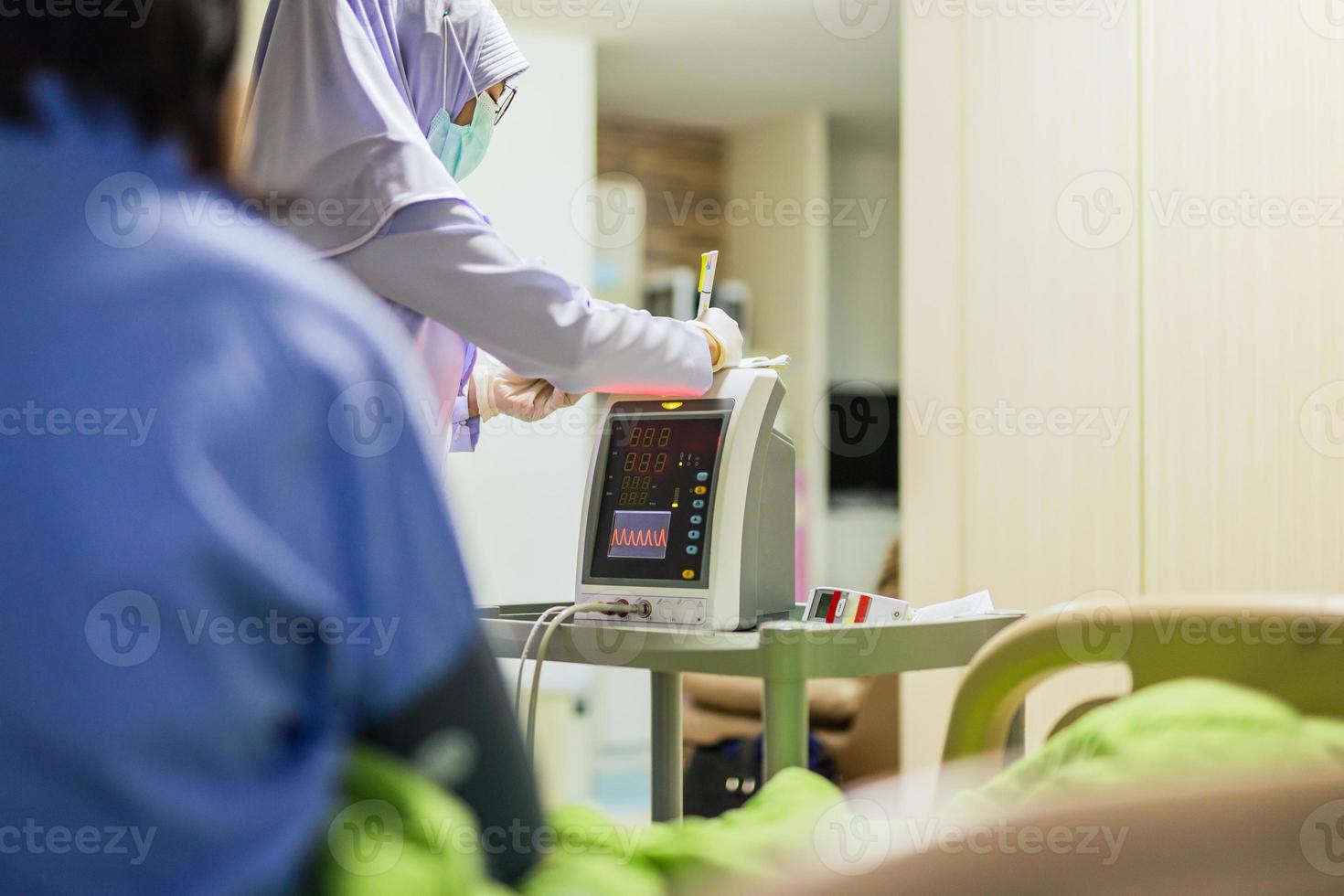 muslimsk sjuksköterska som skriver på Urklipp som mäter blodtrycket hos äldre patient foto