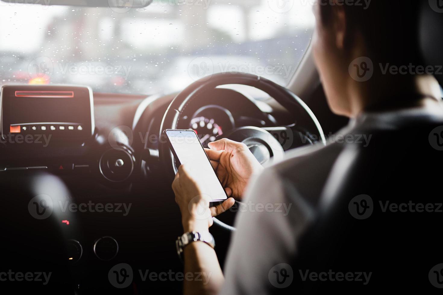 man använder mobiltelefon medan du kör på regnig dag foto