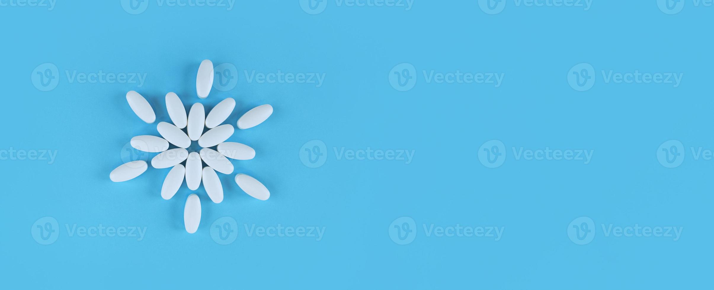 blomma form gjord av vita tabletter på blå bakgrund med kopia utrymme foto