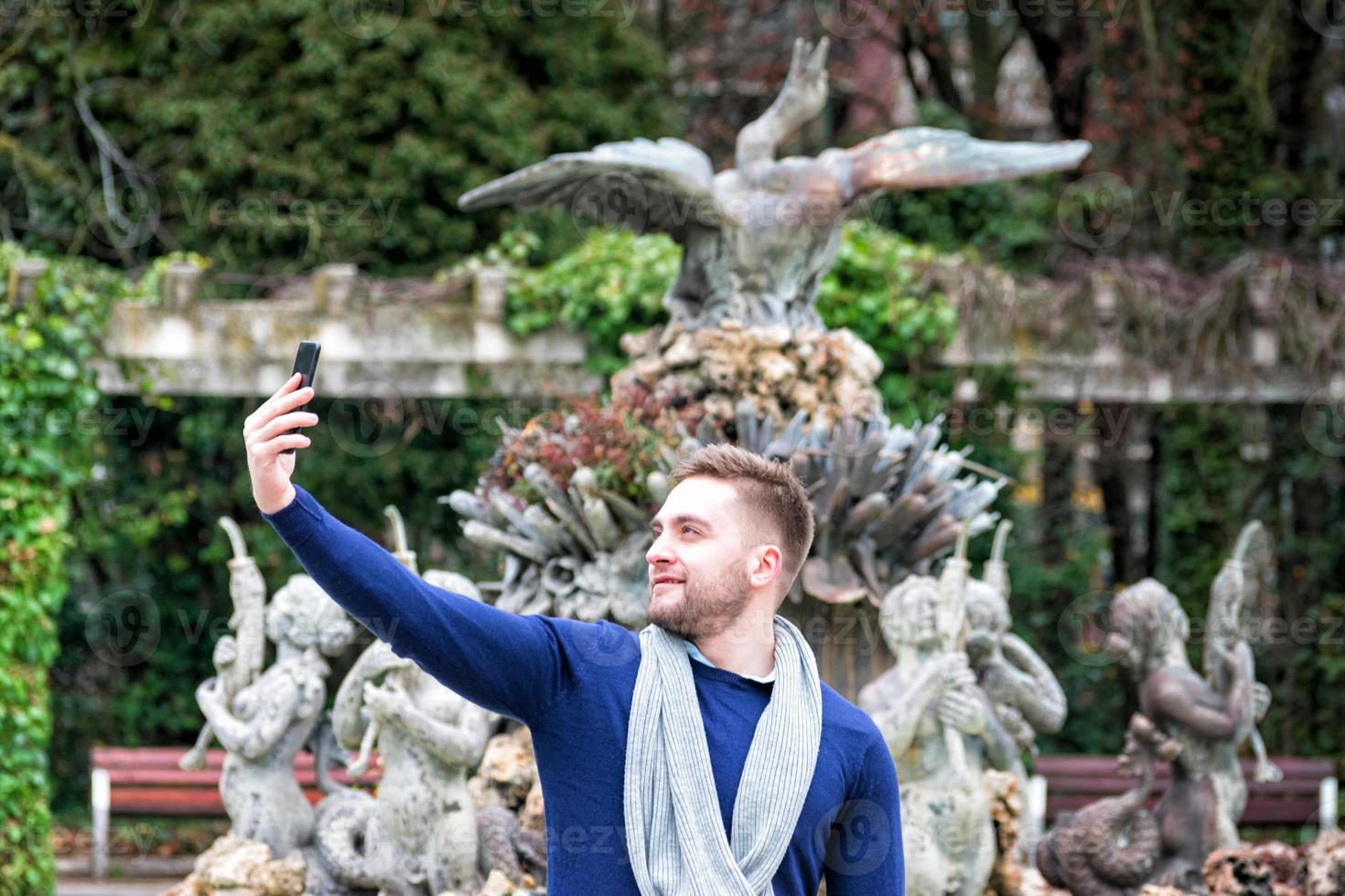 ung man tar en bild med sin mobiltelefon i parken foto