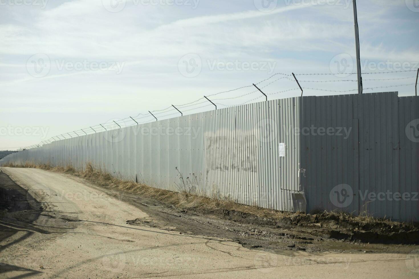 staket i industriell zon. väg längs territorium. textavsnitt mellan staket. foto