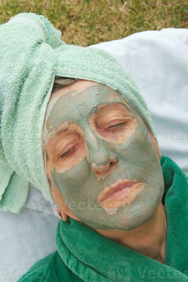 en seniors ansikte är täckt förbi lera ansiktsbehandling mask.stäng upp foto