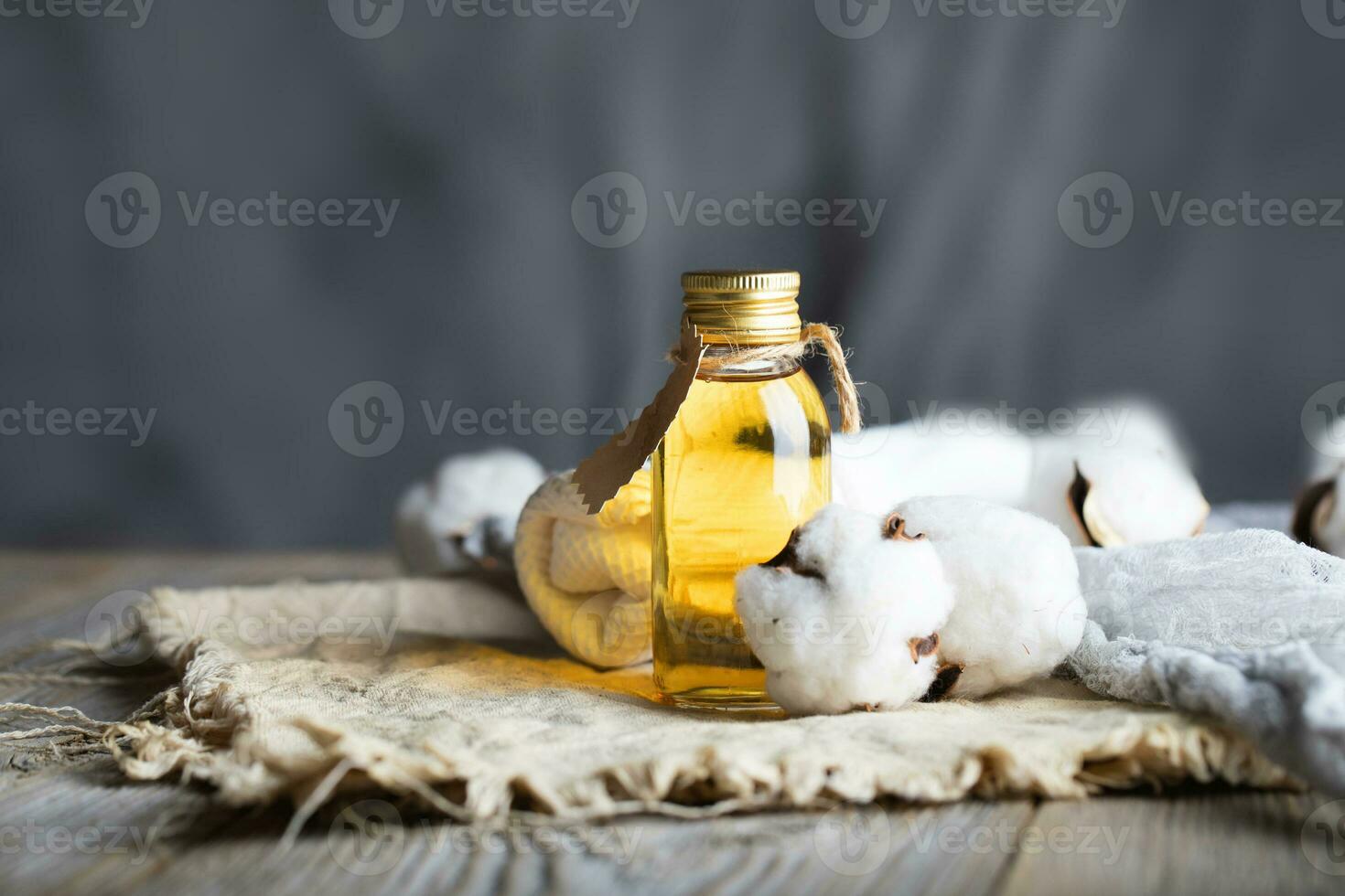 bomullsfrö olja i en glas flaska på en trä- yta. foto