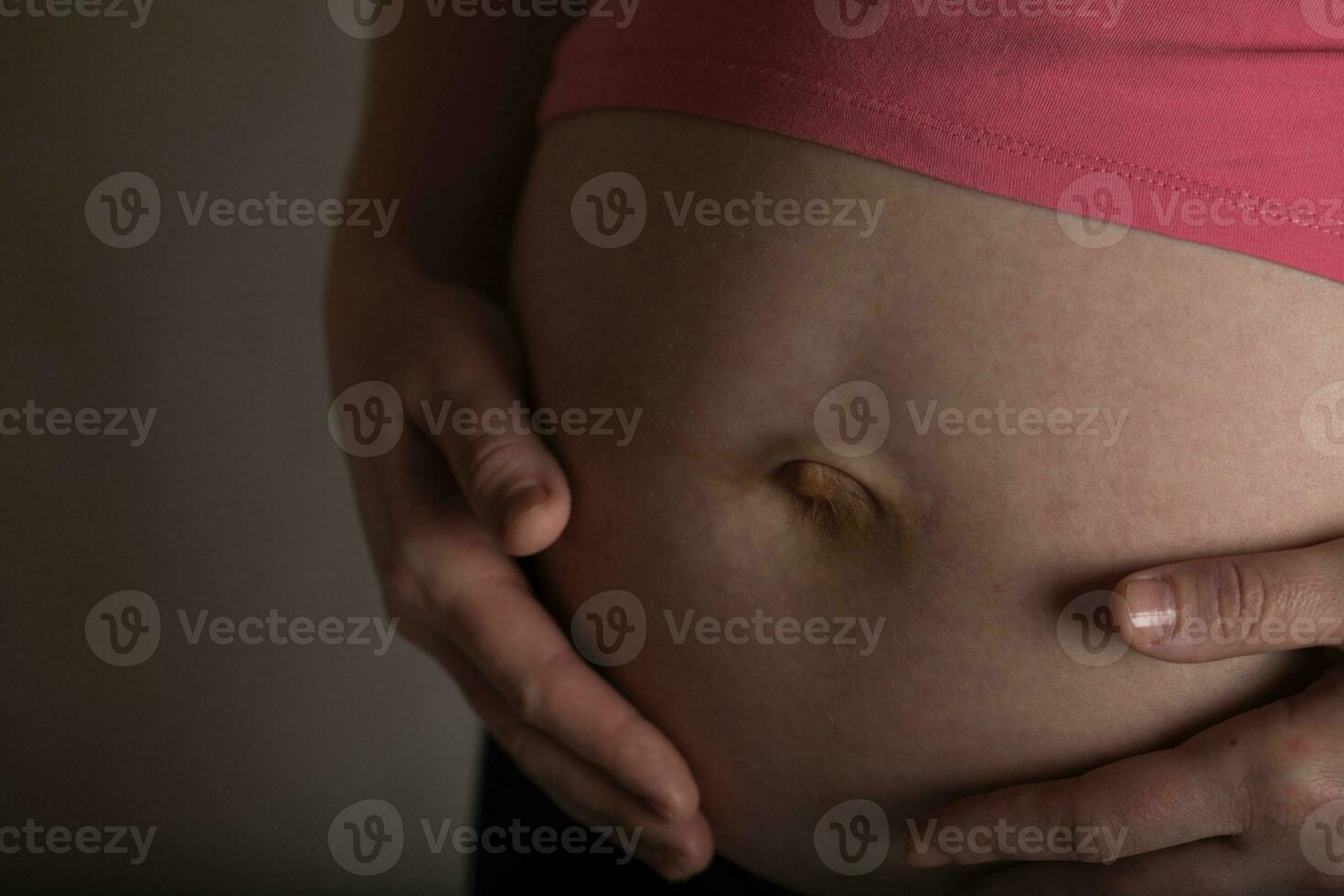 ung gravid kvinna finputsning henne mage. dramatisk ljus. foto