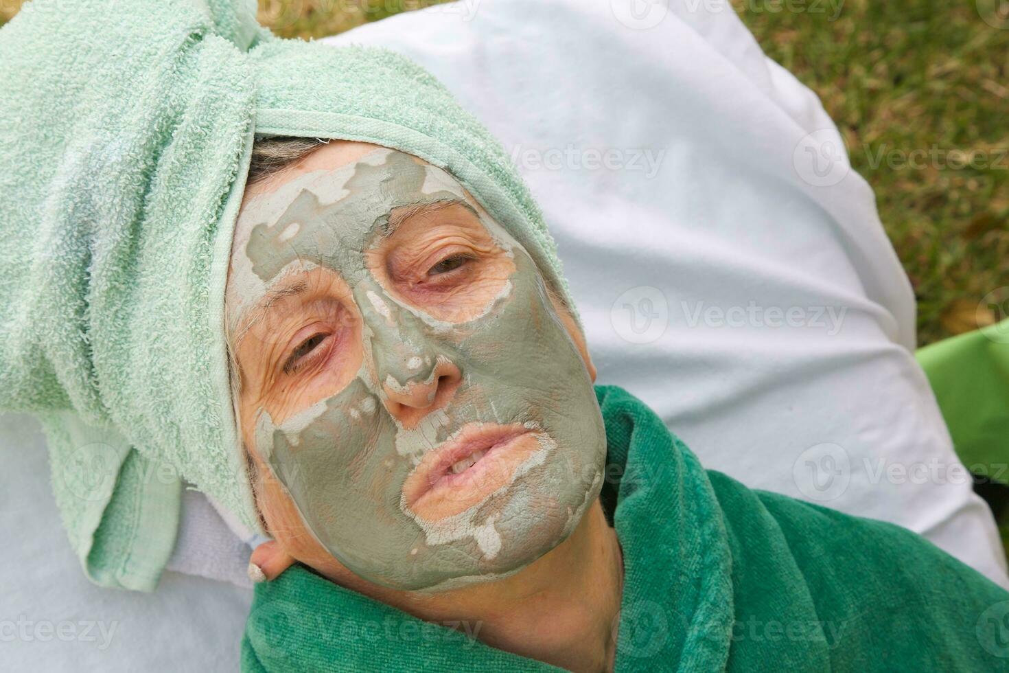 en seniors ansikte är täckt förbi lera ansiktsbehandling mask.stäng upp foto