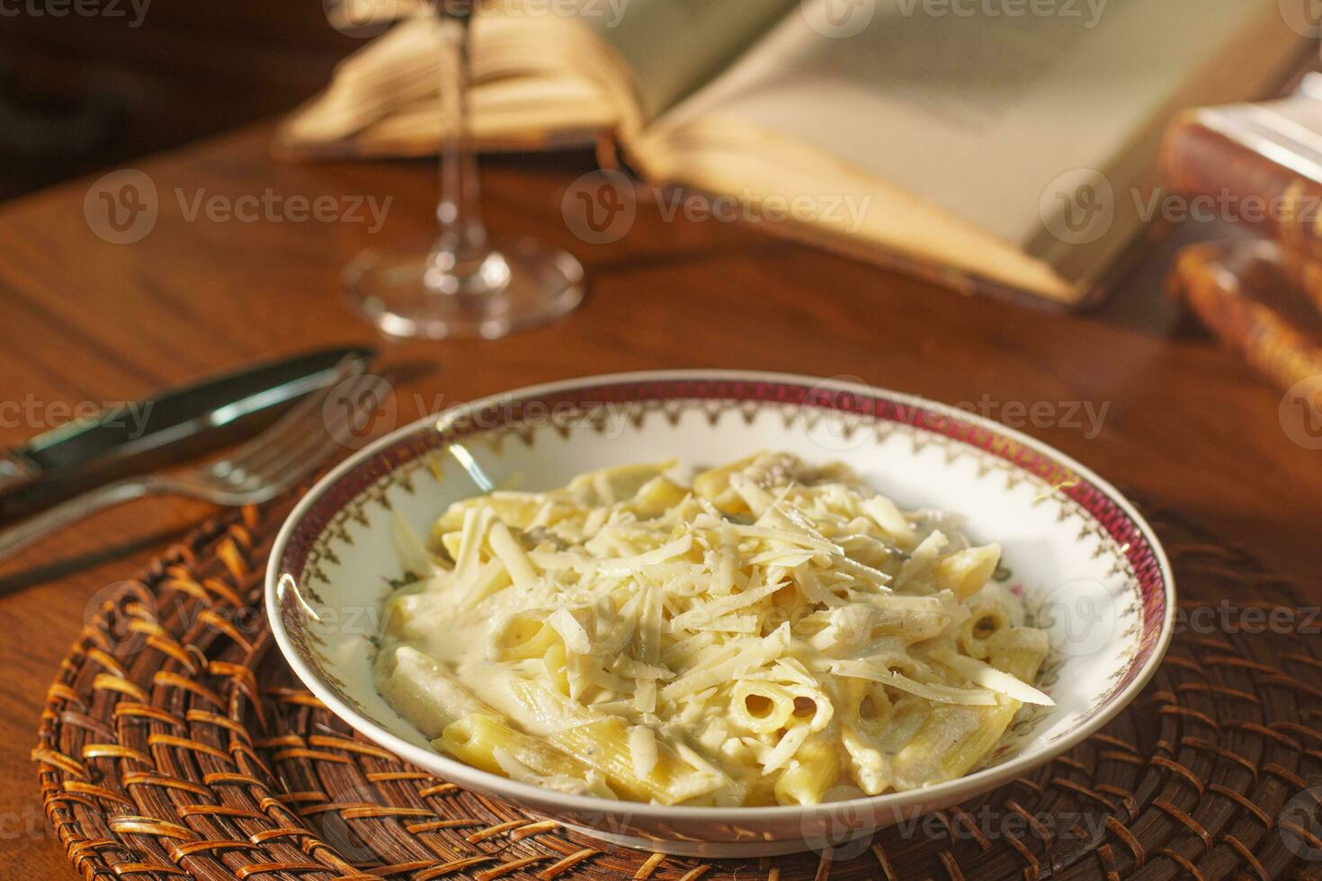 underbar maträtt av penne med vit ost sås. i de bakgrund gammal böcker foto