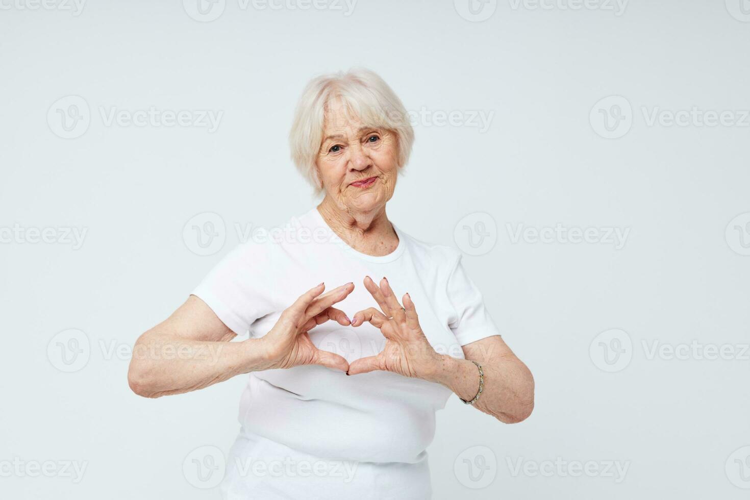 Foto av pensionerad gammal lady i en vit t-shirt ljus bakgrund