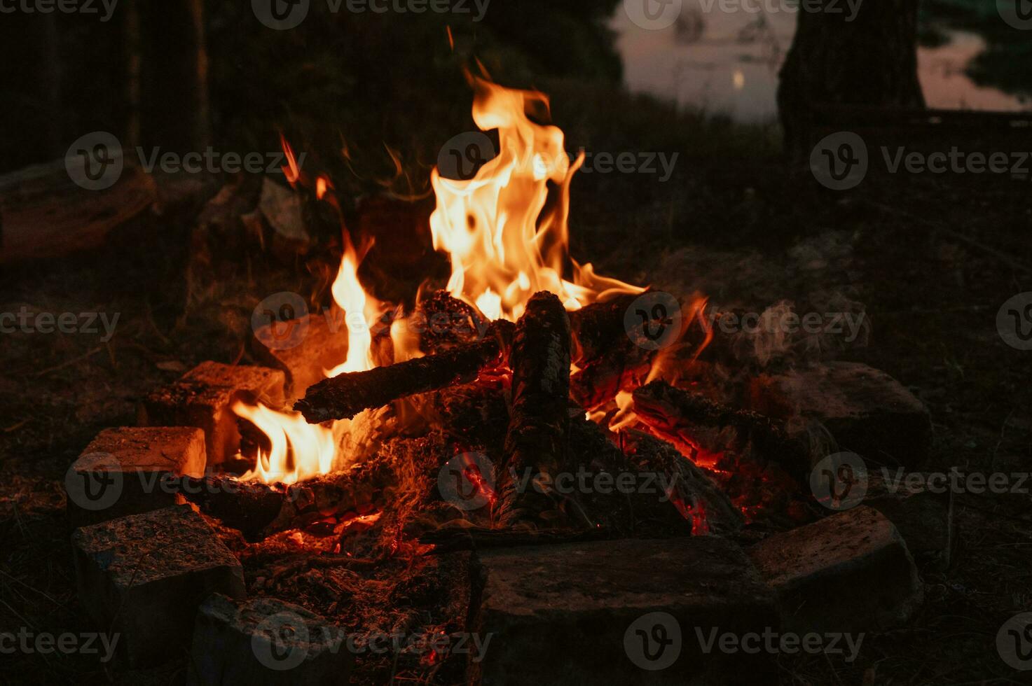 en bål i närbild, lågor, förkolnade bitar av loggar och aska i de öppen luft mot de landskap. camping. foto