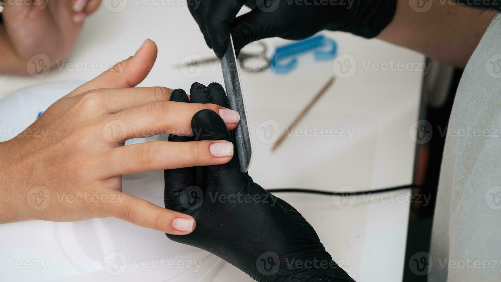 närbild av en manikyr bemästra sågning en nagel fil. de begrepp av salong professionell manikyr foto