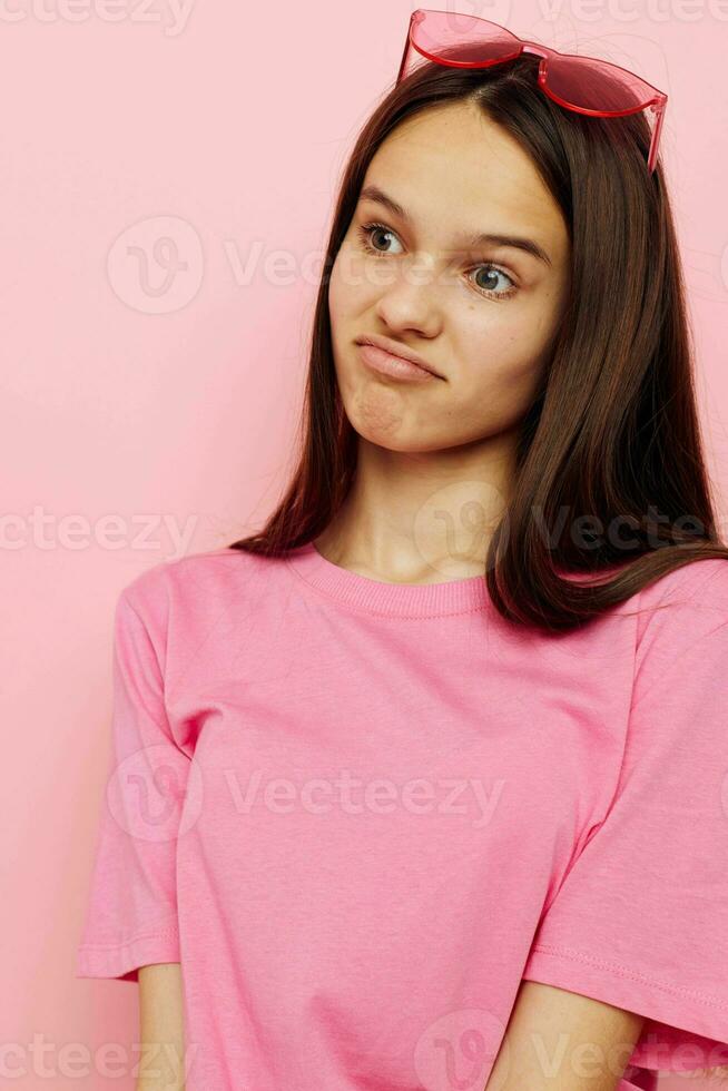 Foto Söt kvinna rosa glasögon och t-shirt hand gest rosa bakgrund