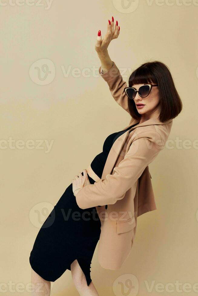 Foto Söt kvinna i solglasögon kort håriga kostym gestikulerar med händer ljus bakgrund
