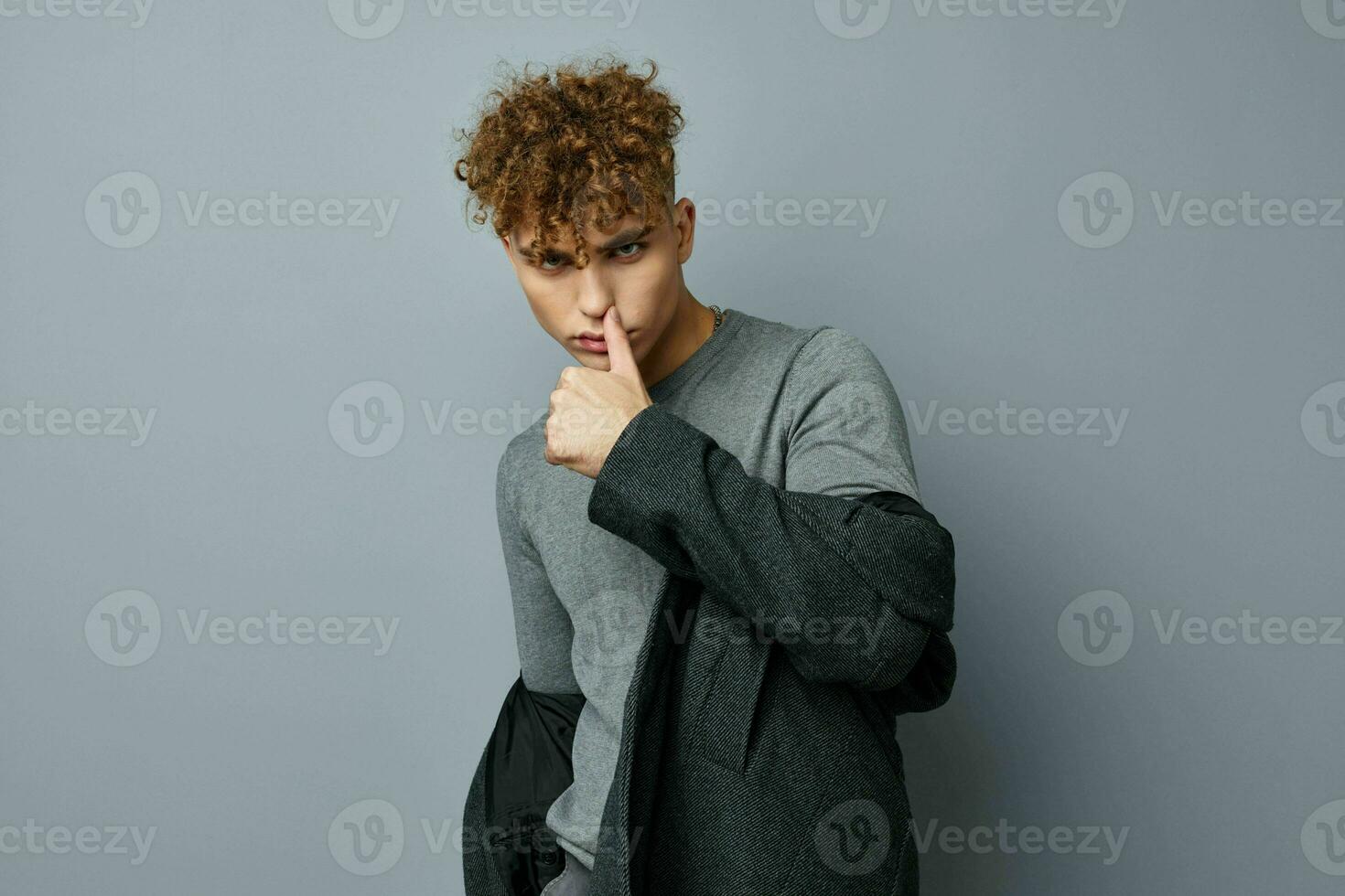 stilig ung man i en grå tröja täcka mode studio isolerat bakgrund foto