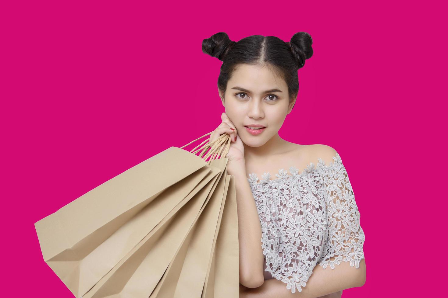 attraktiv shopparkvinna som håller shoppingpåsar på rosa bakgrund foto