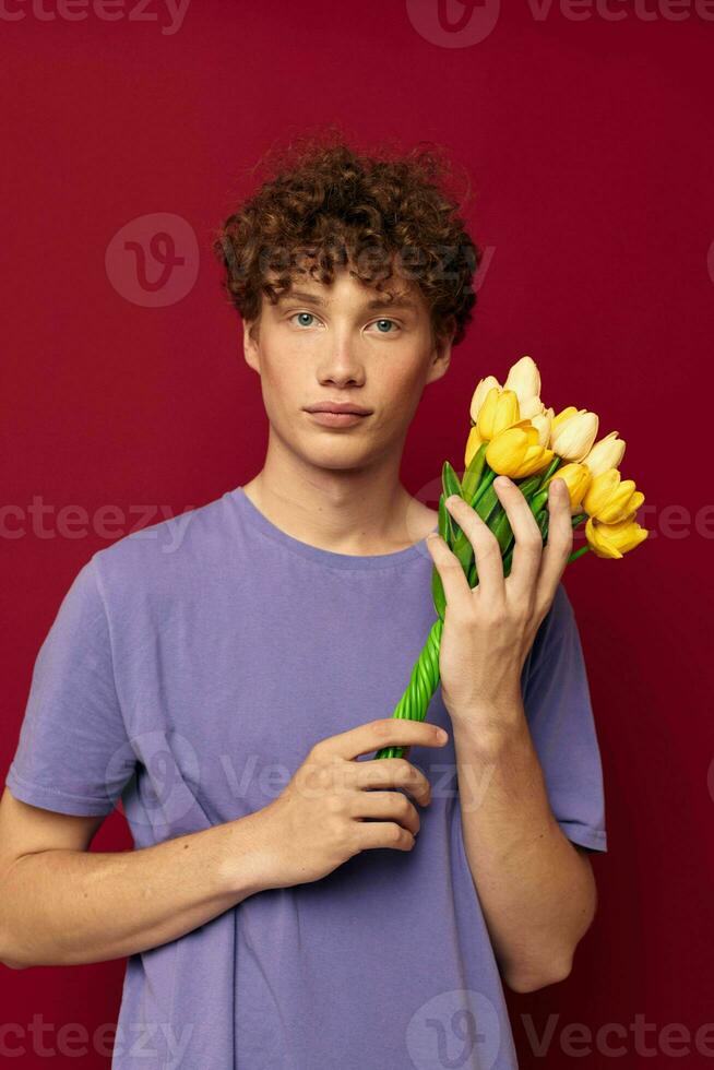 kinky kille innehav en gul bukett av blommor lila t-tröjor isolerat bakgrund oförändrad foto