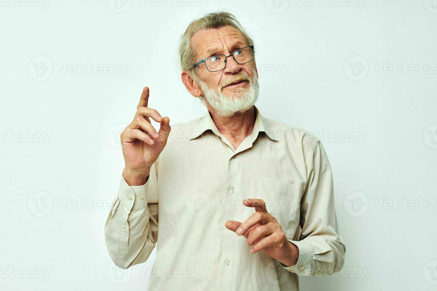 Foto av pensionerad gammal man med en grå skägg i en skjorta och glasögon ljus bakgrund