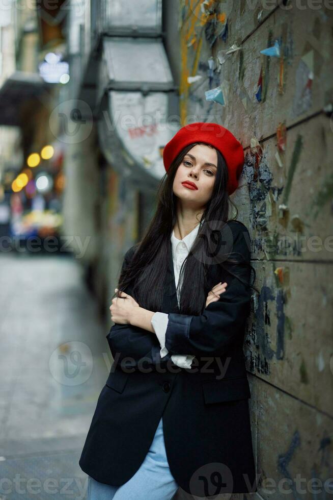 mode kvinna porträtt gående turist i eleganta kläder med röd mun gående ner en smal stad gata, resa, filmiska Färg, retro årgång stil, dramatisk mot en vägg med graffiti. foto