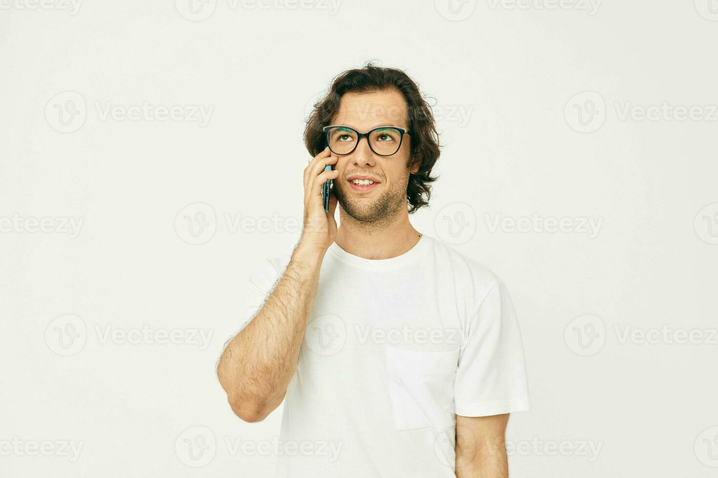 glad man i en vit t-shirt kommunikation förbi telefon isolerat bakgrund foto