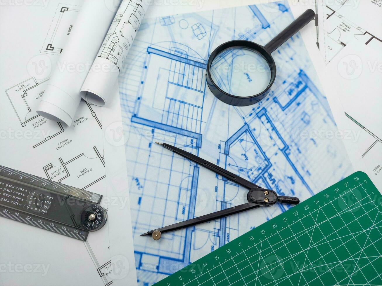 arkitekt ingenjör kontor skrivbord. plan planer och hus modell med linjal, kompass, och förstoringsglas glas foto