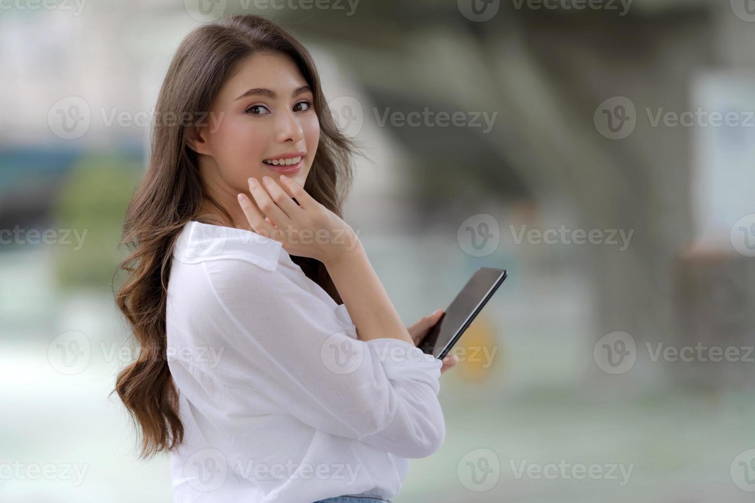 porträtt av ung kvinna med smiley ansikte med en telefon promenader i en stad foto