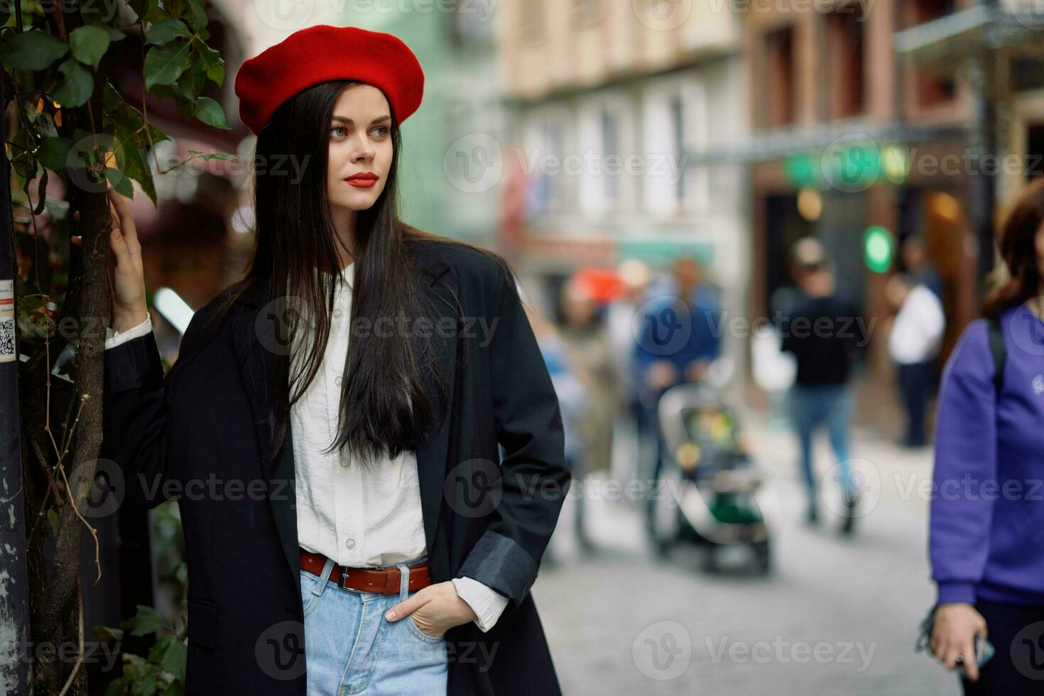 kvinna mode modell promenader på de gata i de stad Centrum bland de folkmassan i en jacka och röd basker och jeans, filmiska franska mode stil Kläder, resa till istanbul foto