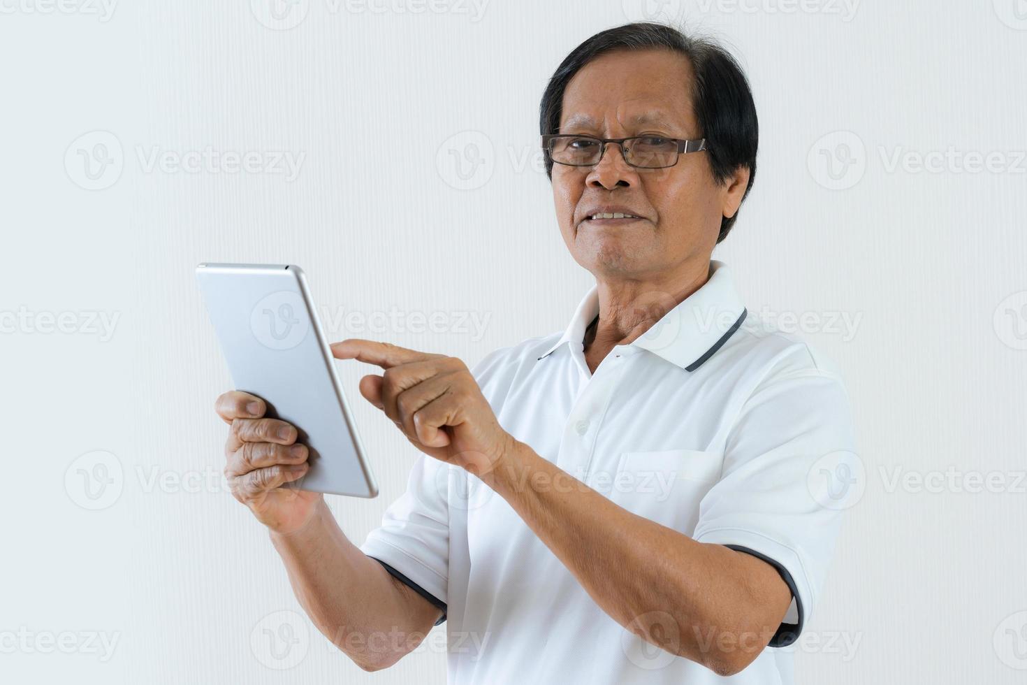 stående av den asiatiska äldre mannen som använder en digital minnestavla foto
