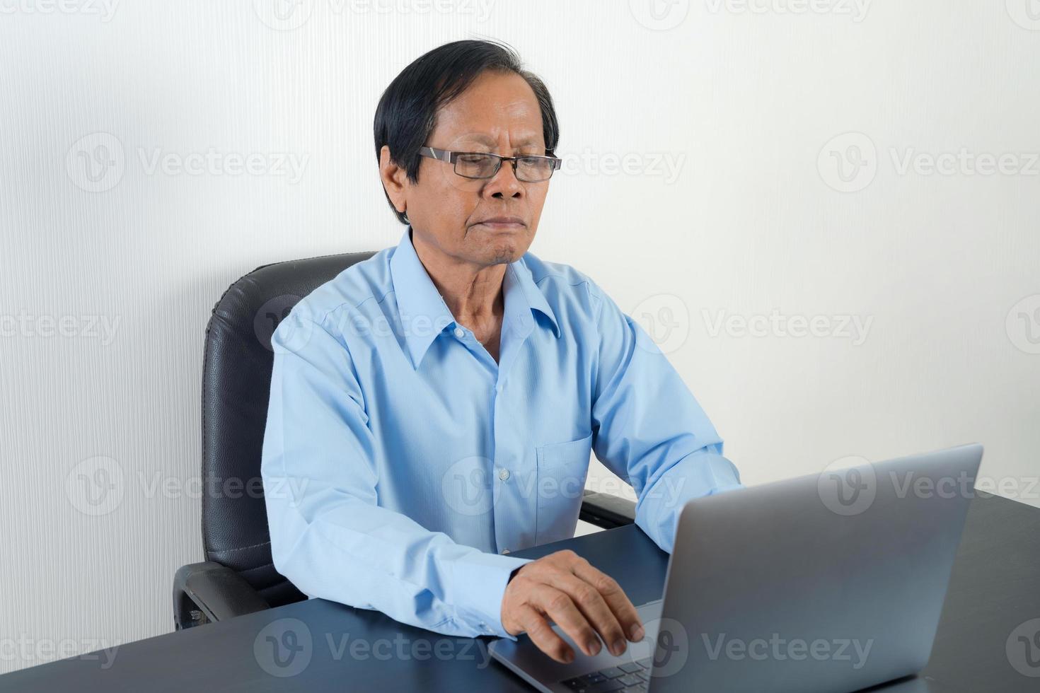 stående av den asiatiska äldre mannen som använder bärbara datorn foto