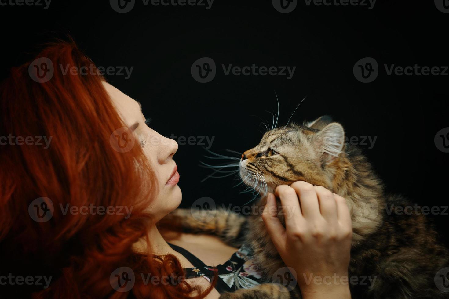 rödhårig kvinna kramar och slår fluffig katt foto
