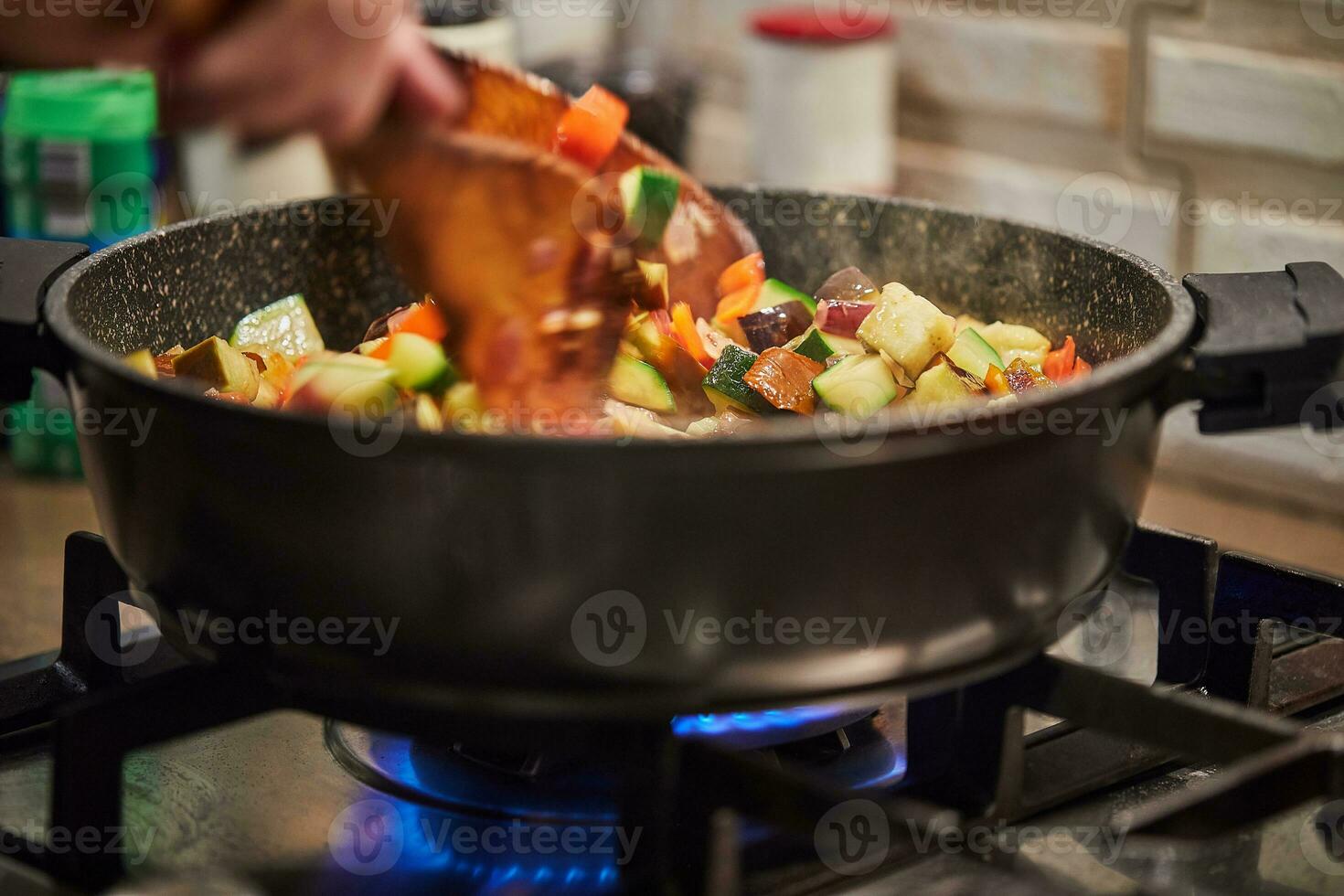 franska kök ratatouille sallad shchef rör om i fräsning panorera på gas spis foto