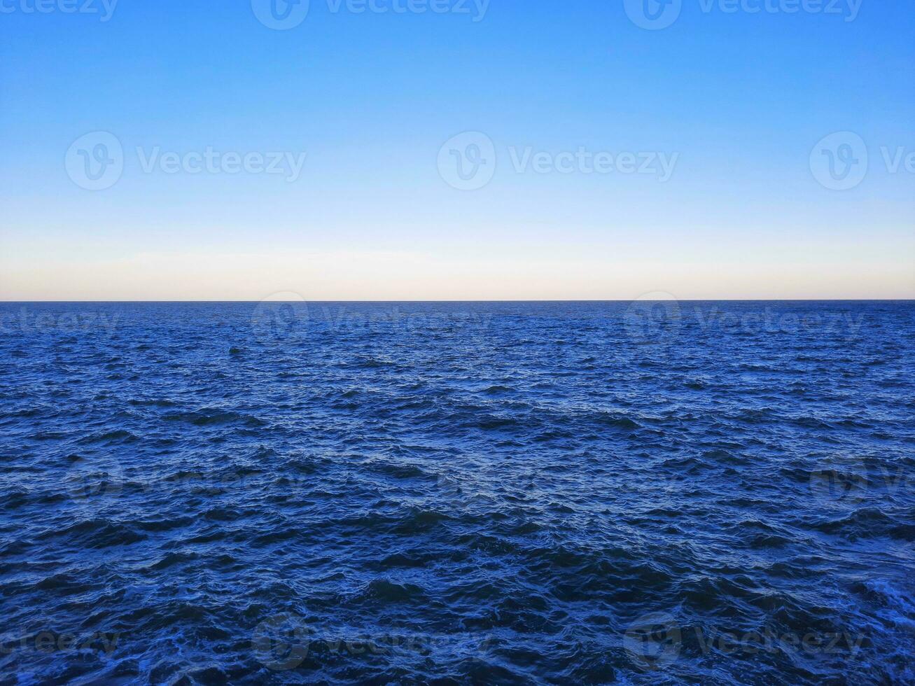 blå himmel och hav med krusningar på de yta. defokusering suddig transparent blå hav yta textur med stänk och bubblor. vatten vågor med lysande mönster textur bakgrund. foto
