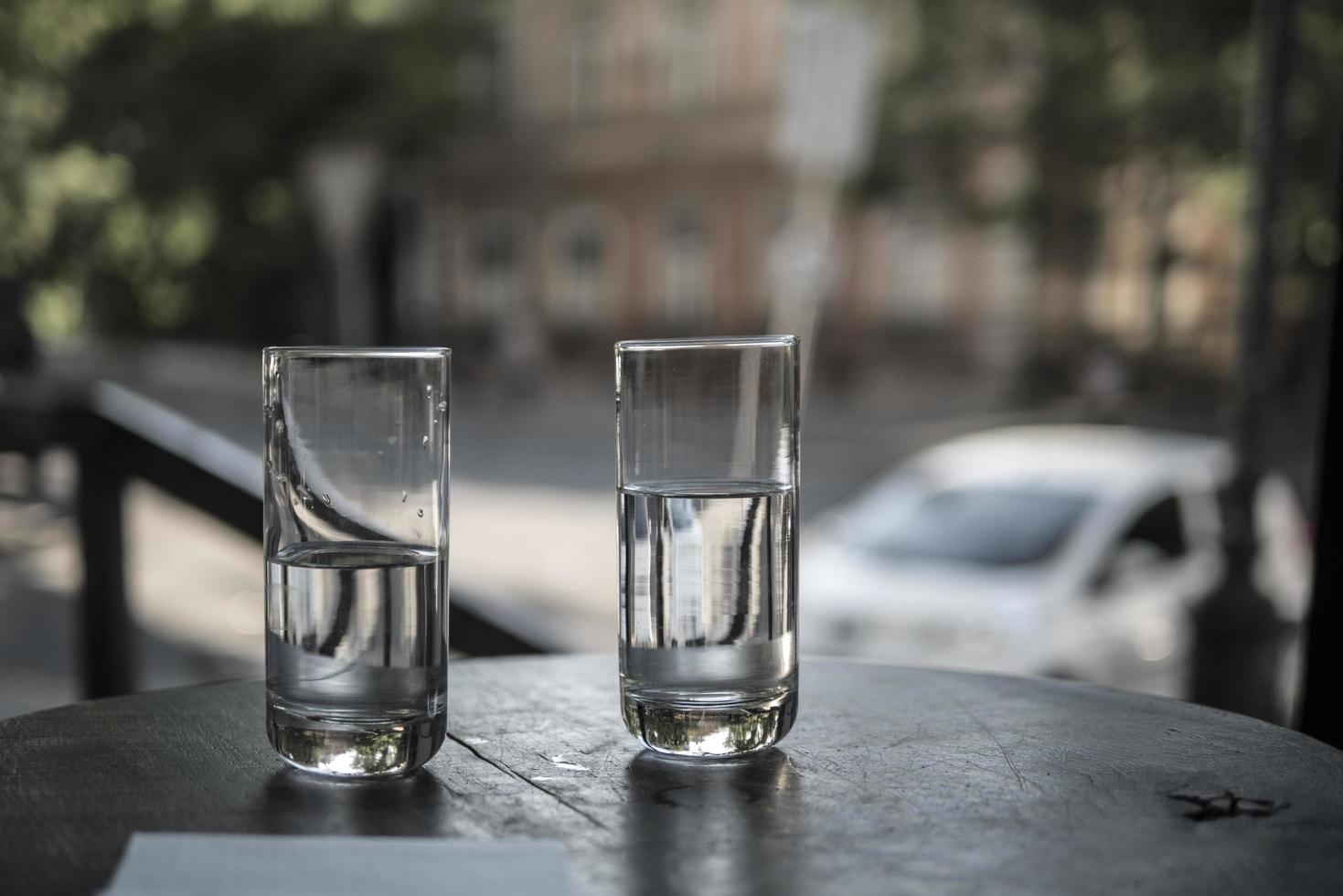 två glas vatten står på ett bord i en restaurang på bakgrunden av stadens gator foto