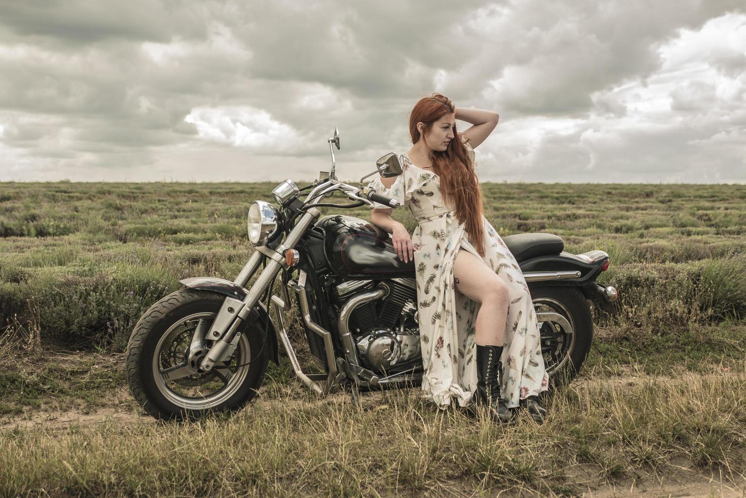 rödhårig flicka i en vit klänning och stövlar tillsammans med en motorcykel lavendel fält foto