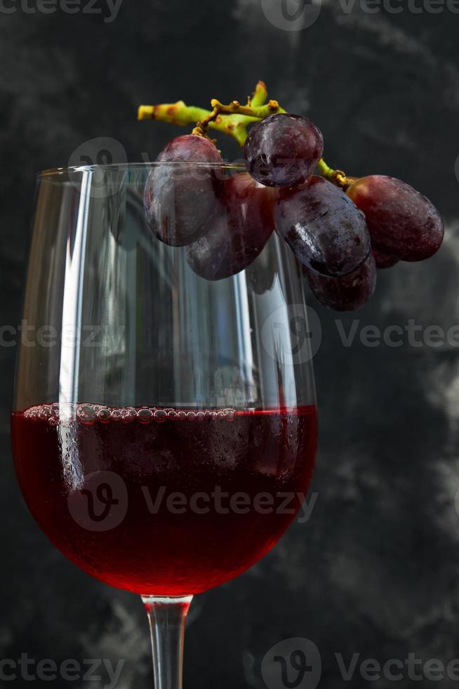 glas vin med druvor på en mörk bakgrund foto