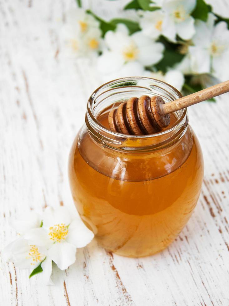 honung med jasminblommor på en träbakgrund foto