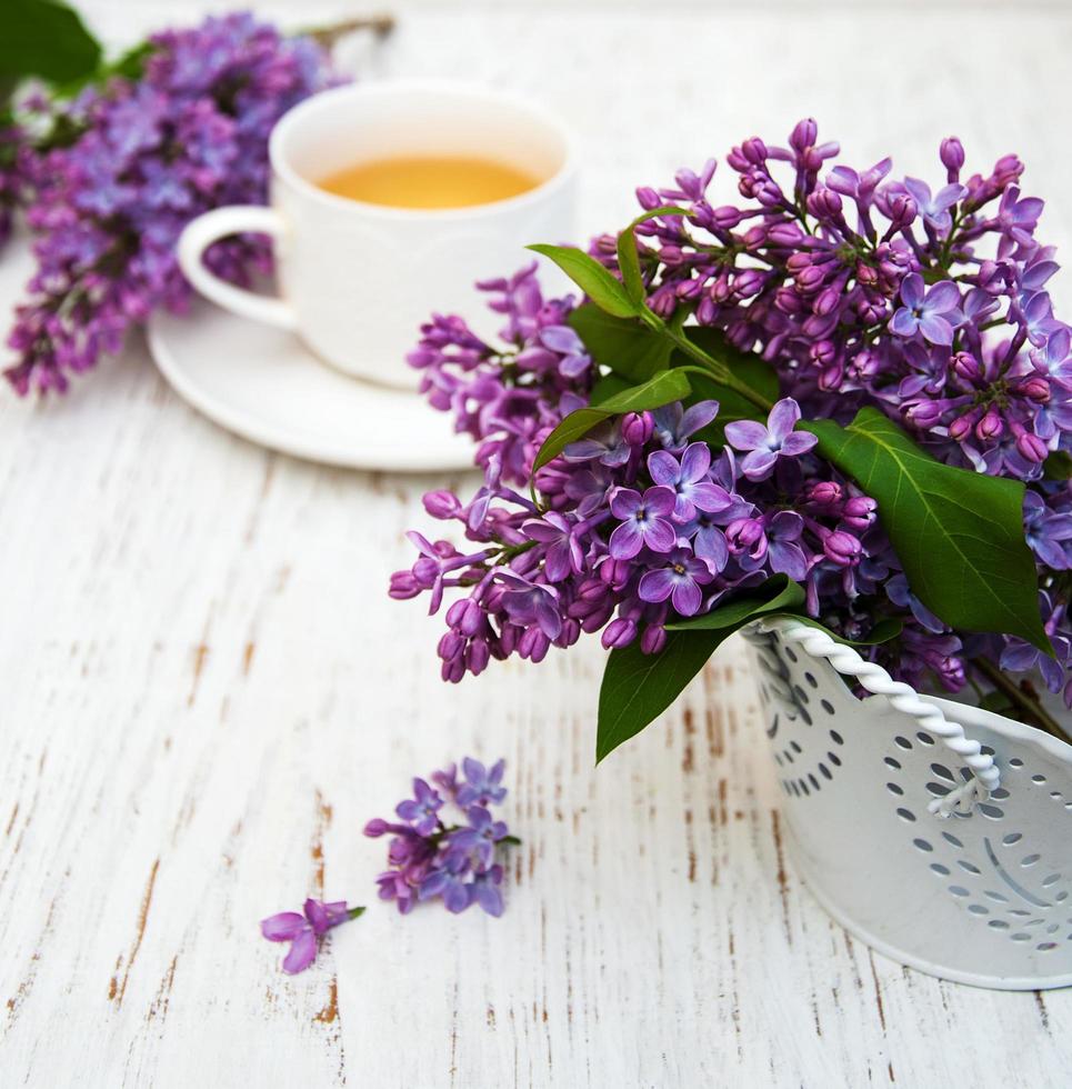 kopp te och lila blommor foto