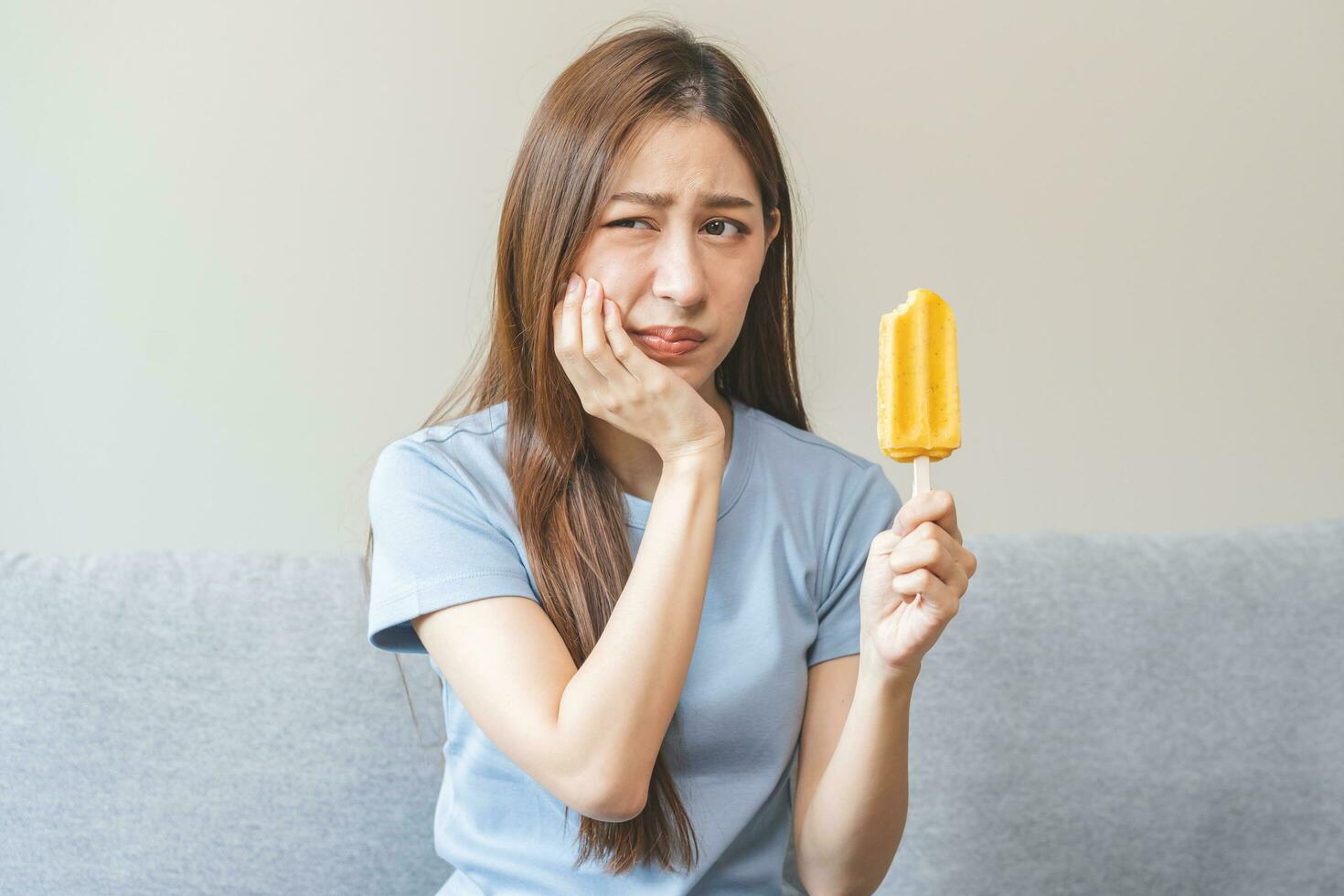 ansikte uttryck lidande från känslig tänder och kall, asiatisk ung kvinna, flicka känsla ont, smärta äter is grädde, lolly. tandvärk molar- tand på Hem, dental problem isolerat på vit bakgrund. foto