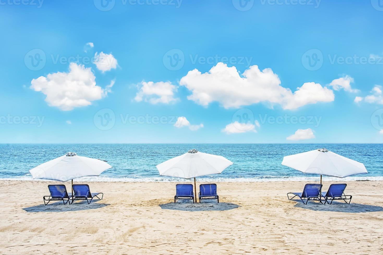 stolar och paraplyer på en tropisk strand foto