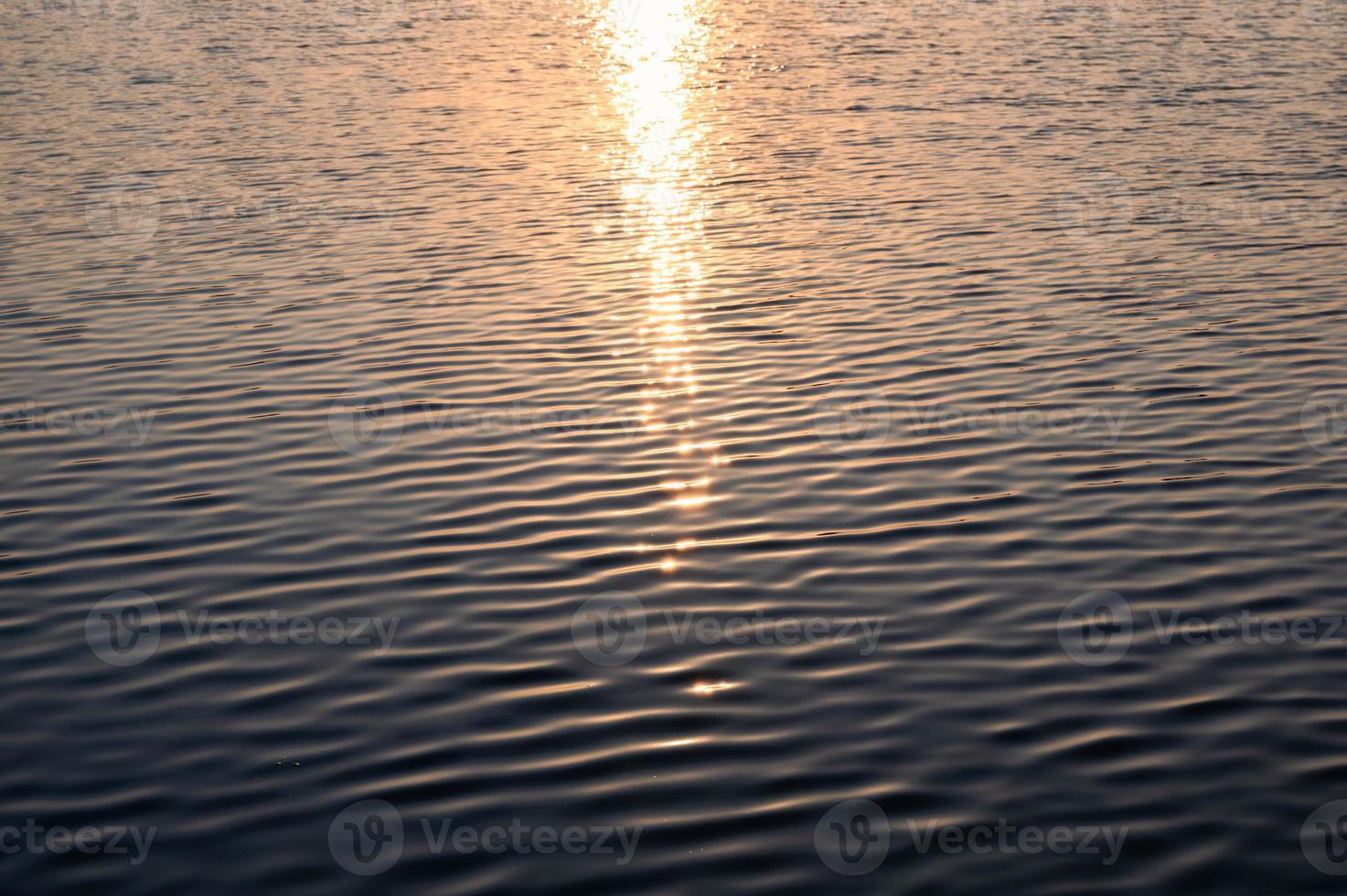 solsken glödande på krusat vatten i sjön foto