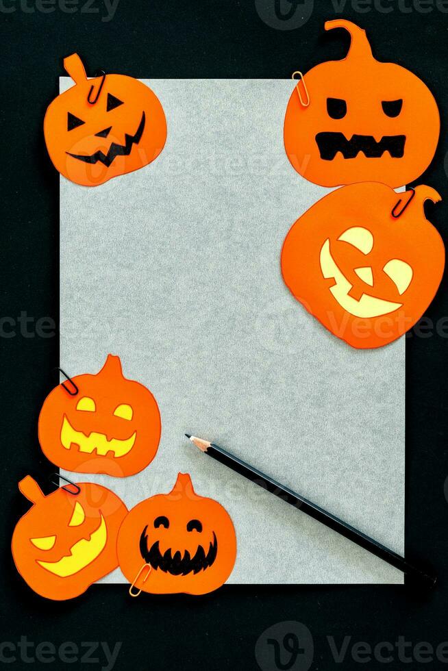 halloween kontor skrivbord, grå papper, penna och pumpa papper skära på svart tabell. foto