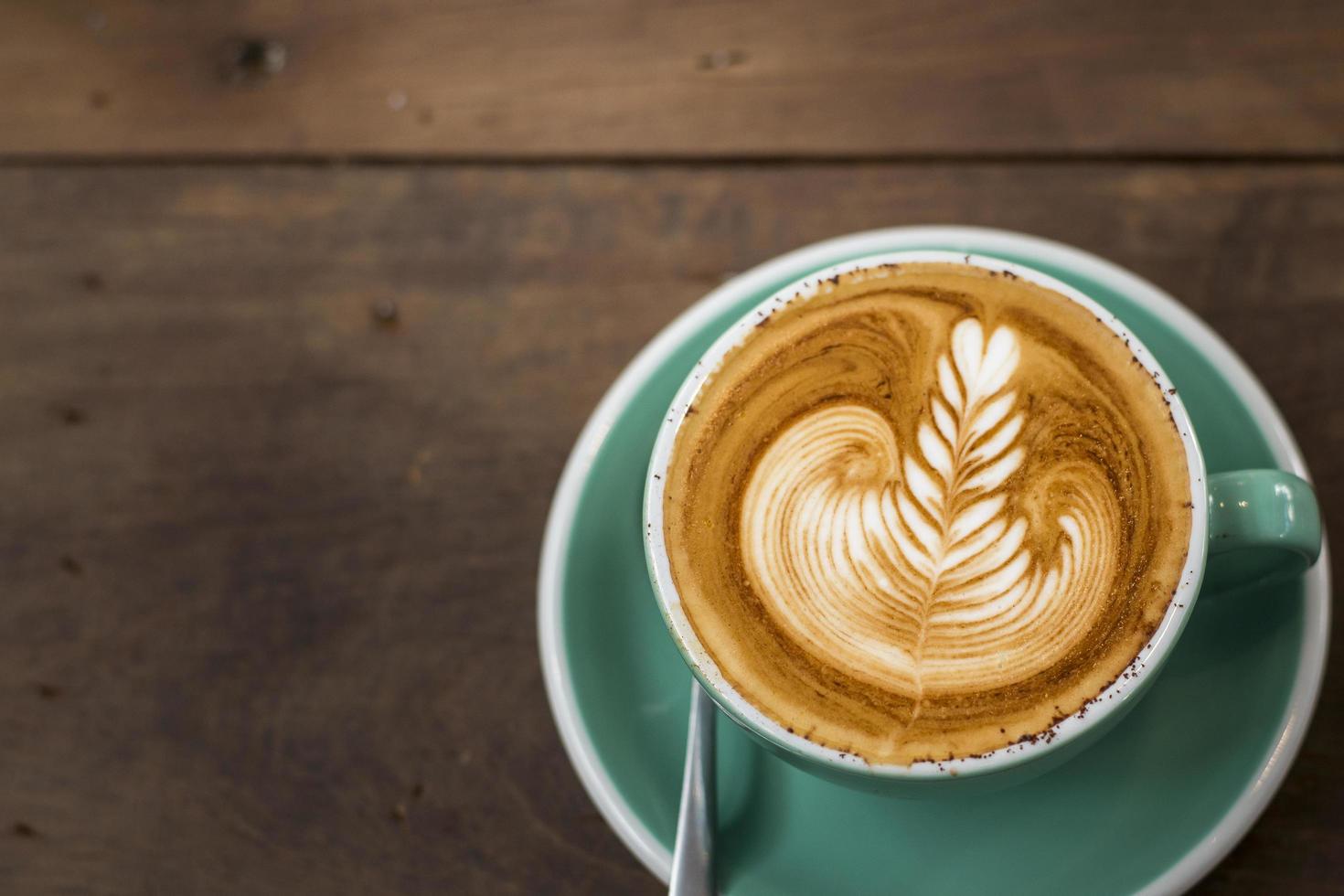 varm cappuccino med lattekonst på träbakgrund foto