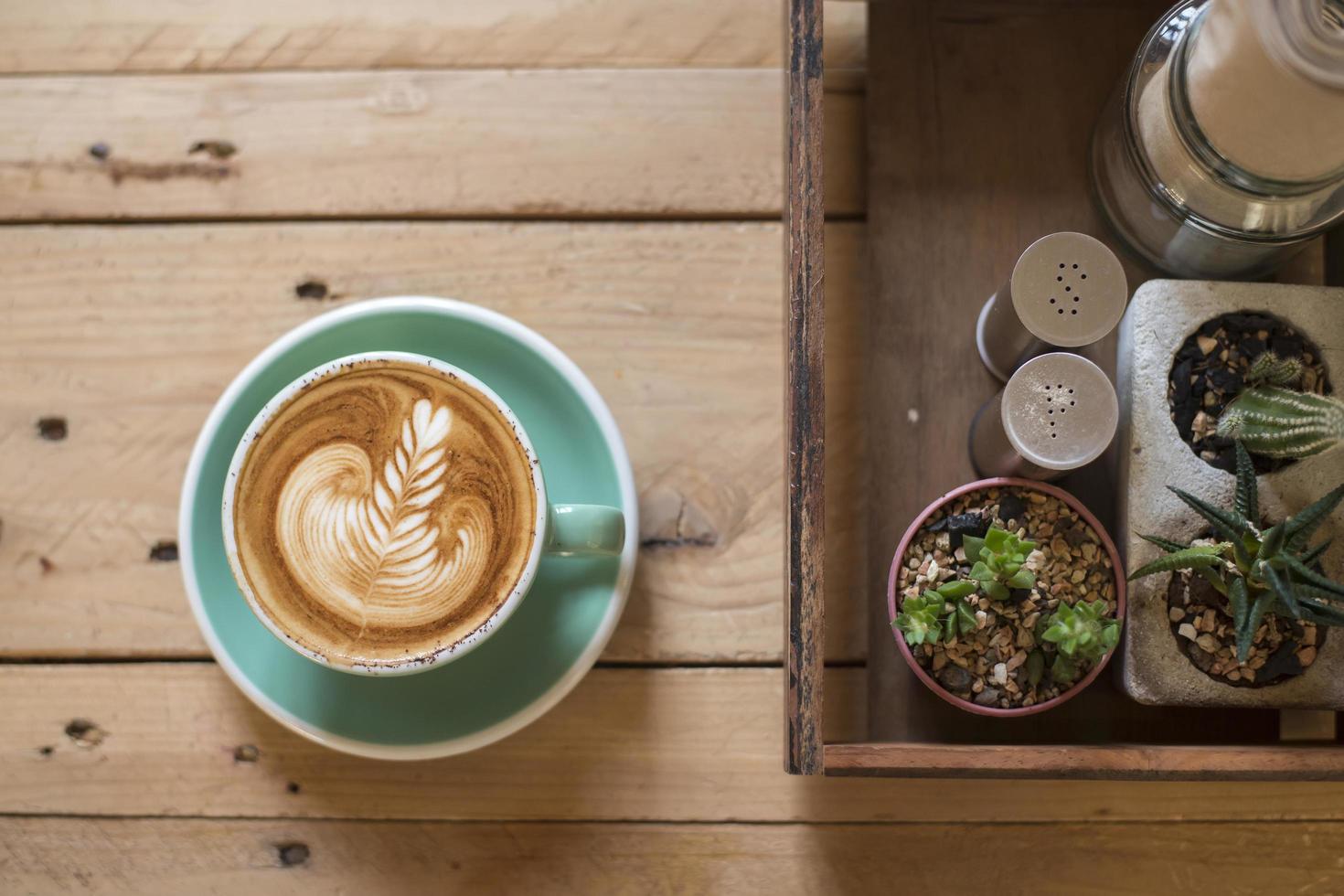 varm cappuccino med lattekonst på träbakgrund foto