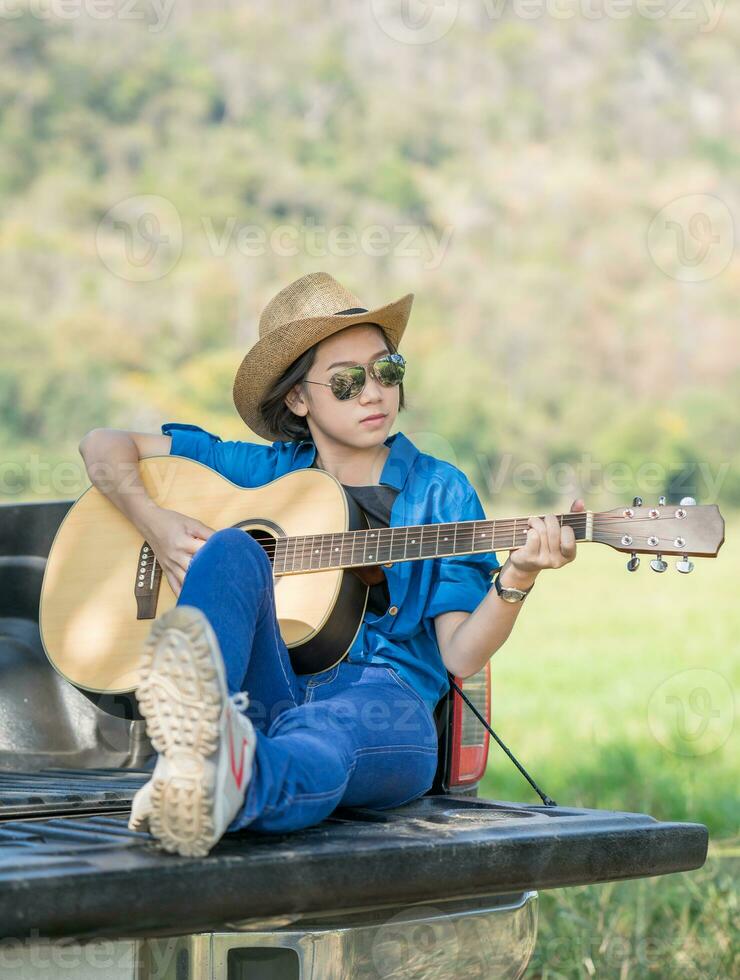 kvinna ha på sig hatt och spelar gitarr på plocka upp lastbil foto