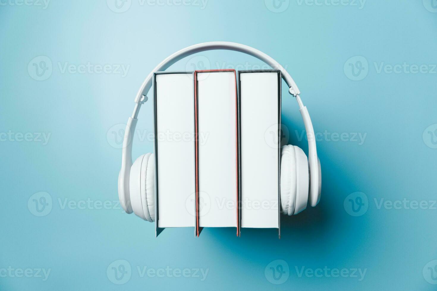 vit hörlurar med stack av böcker på blå bakgrund. audio böcker eller modern utbildning begrepp. kopia Plats för text. distans utbildning, e-learning begrepp. topp se med Plats för din text. foto