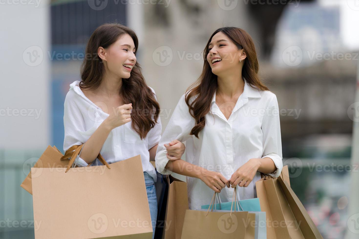lyckliga vänner som handlar två unga kvinnor håller påsar foto
